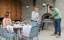people gathered around Great Outdoor Pizza Ovens gray Alfa Ciao outdoor wood-fired pizza oven